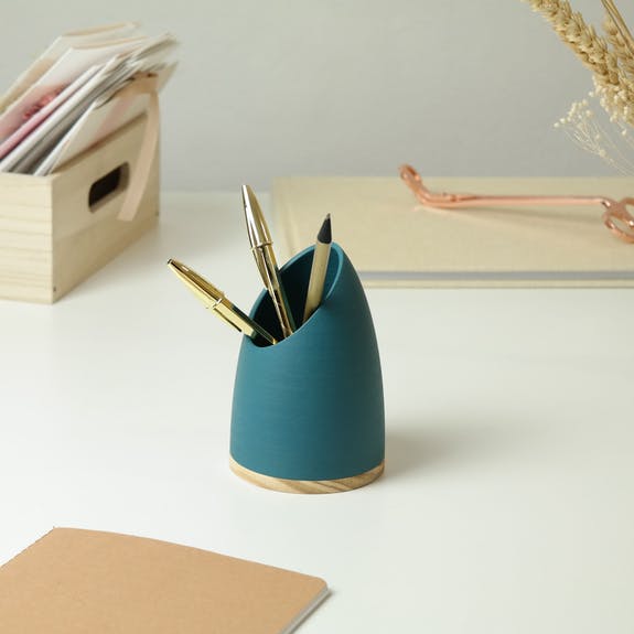 blue pen pot with stationary in it on a white home office desk