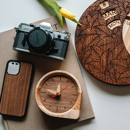 wooden desk clock next to canon camera and iPhone on white desk