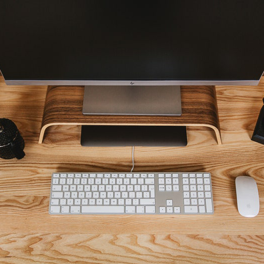 Halostands monitor riser single, on desk next to Mac keyboard 