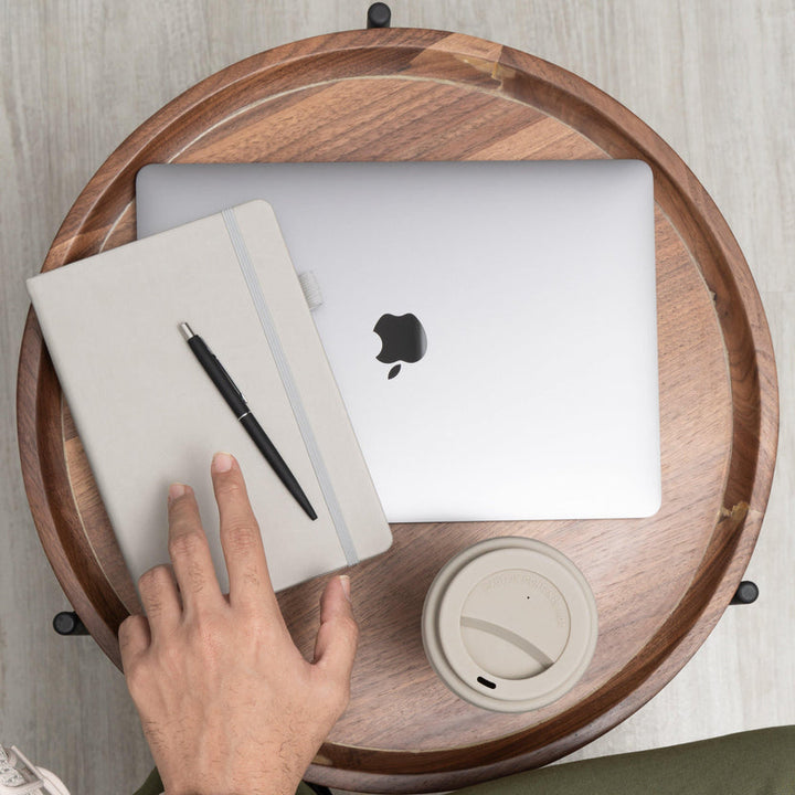 dot grid journal next to apple MacBook on a table with coffee