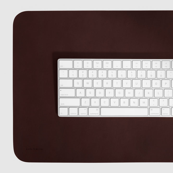 close up of Apple keyboard on top of leather desk mat by carl friedrik