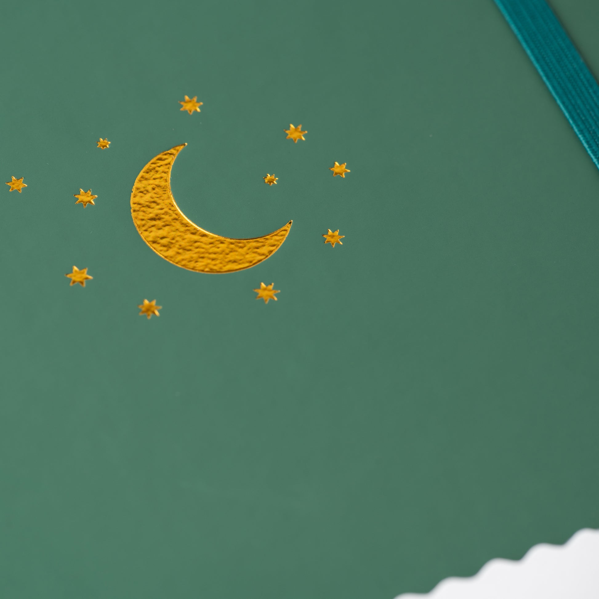 closeup of the gold moon and stars on the front of a green yop and tom notebook