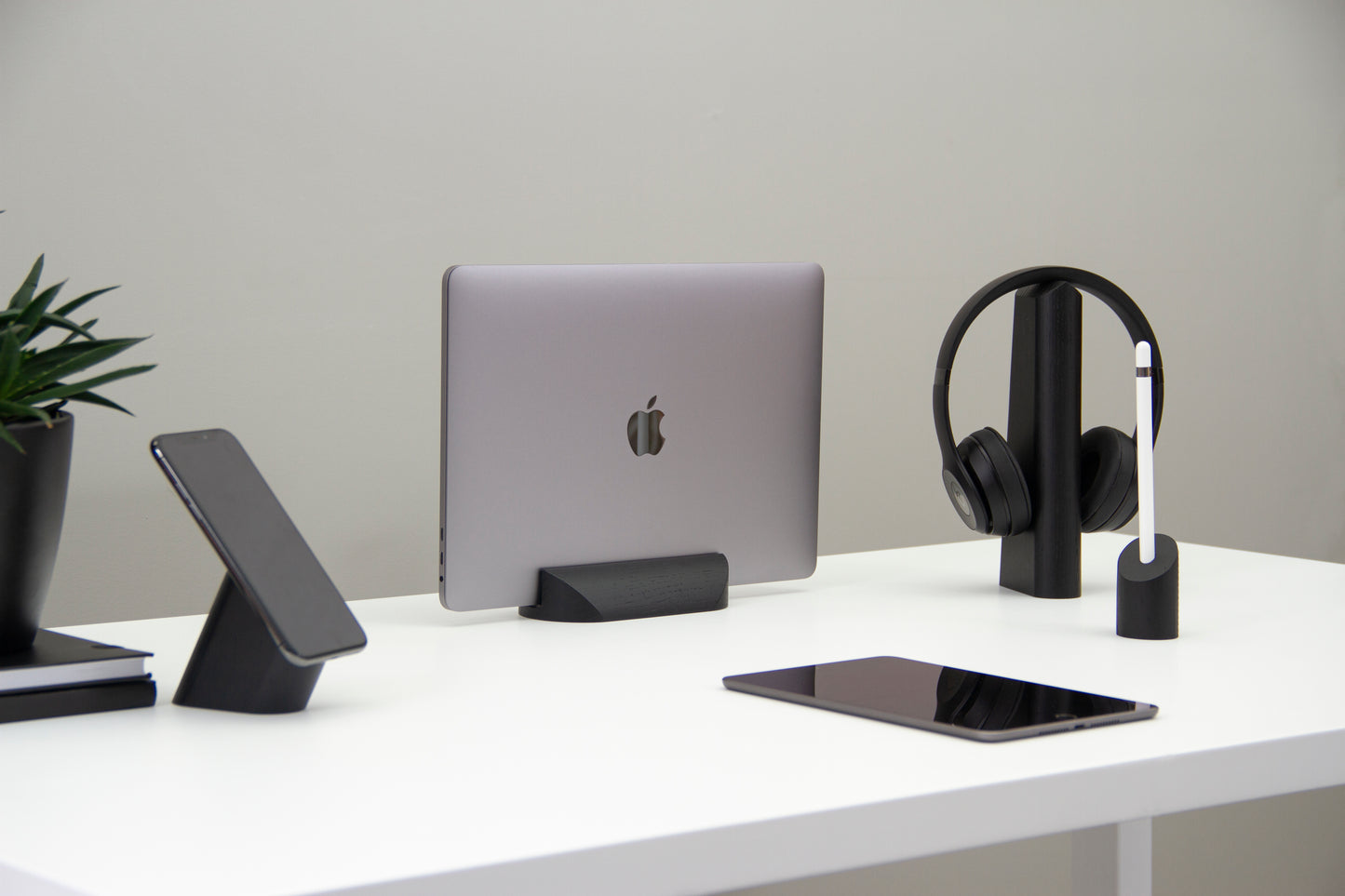 Side angle showing a desk with woodendot accessories including mobile phone stand, MacBook holder and Apple Pencil stand